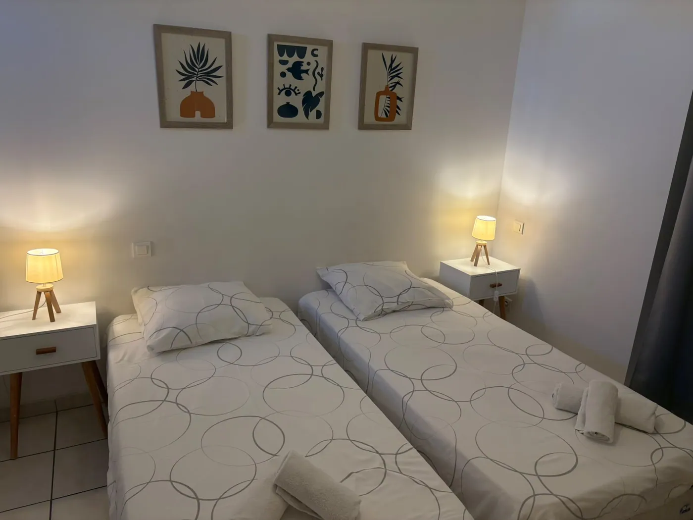 Chambre 1 du Café Arnaud à Ruoms : deux lits simples, tables de chevet et tableaux