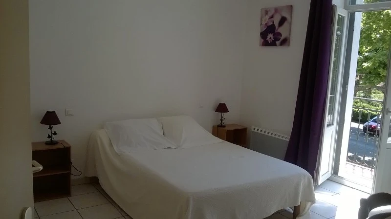 Chambre double du Café Arnaud avec porte-fenêtre ouverte sur les platanes