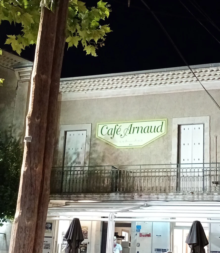 L'enseigne éclairée du Café Arnaud un soir d'été à Ruoms